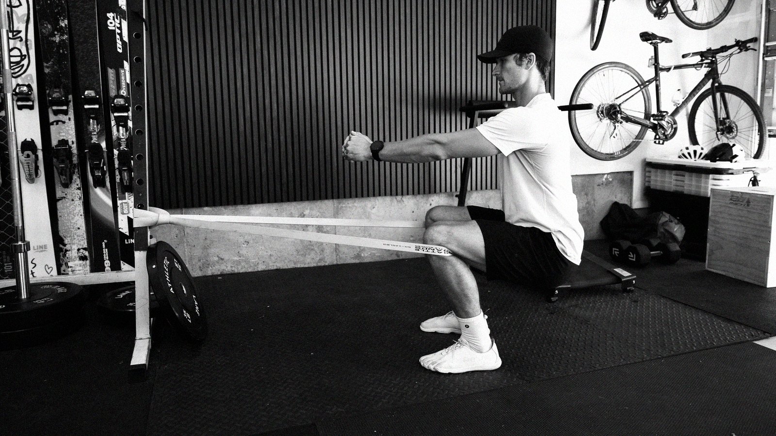 Connor pulling a band into a squat position in his garage gym