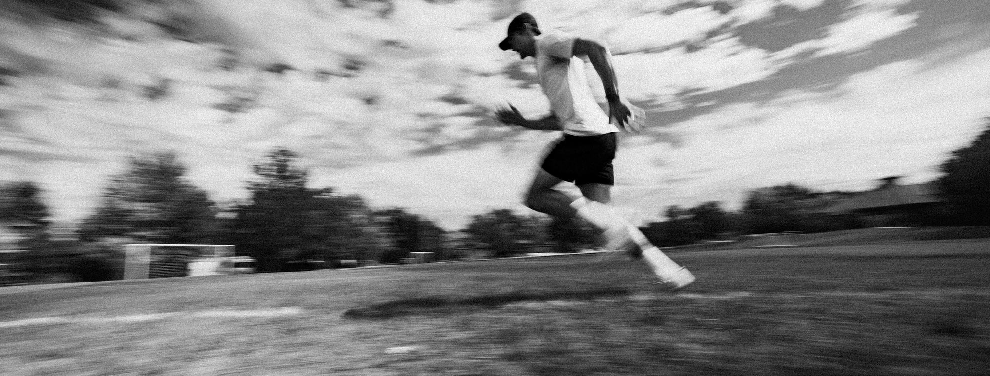Connor sprinting across a field, the sky blurred behind him