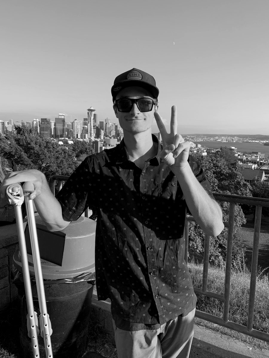 Connor on crutches at Kerry Park in Seattle, peace sign up, the Space Needle behind him, days after his third reconstruction